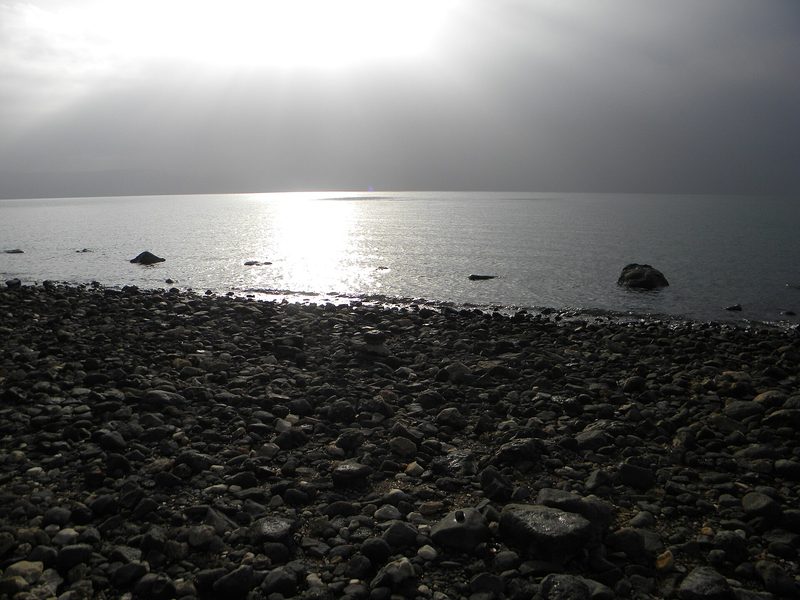 The Sea of Galilee at Tabgha, calm water and the far shore under a clear sky.