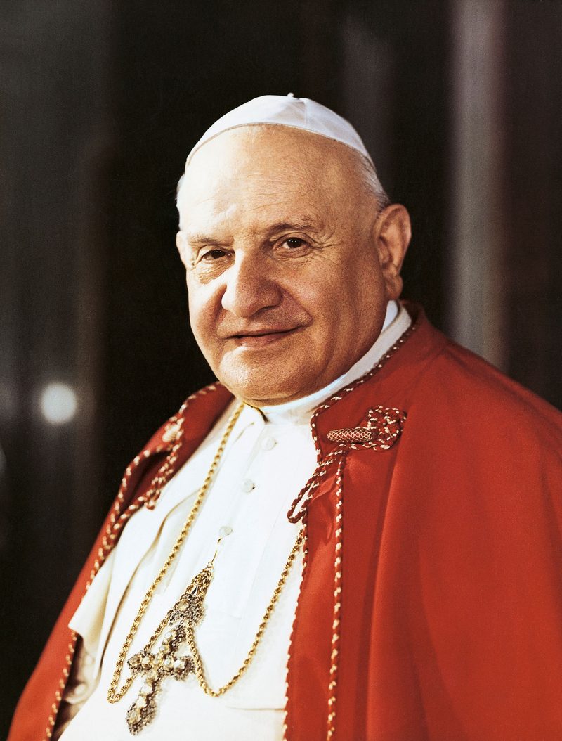 A color photograph of Pope St. John XXIII smiling, in red mozzetta and stole.