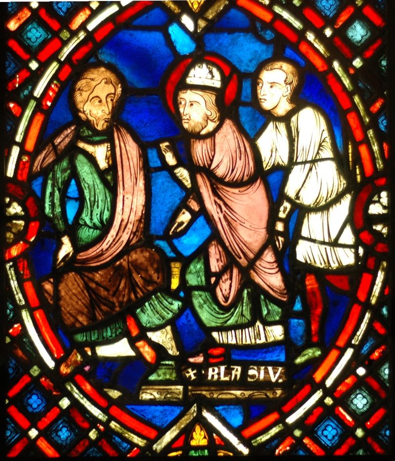 Stained-glass window showing St. Blaise as a bishop with two other figures.