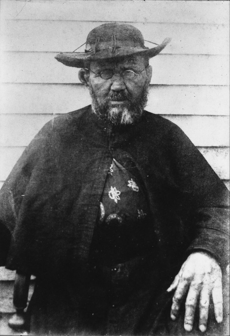 Black-and-white photograph of St. Damien of Molokai in a wide-brimmed hat and dark cassock.
