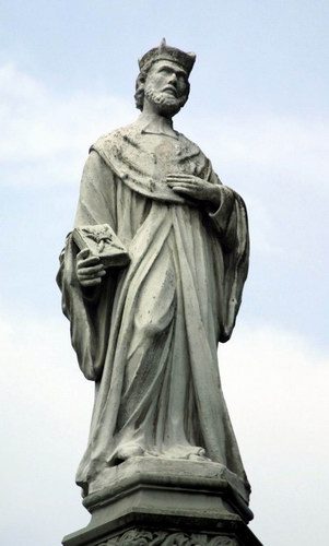 Stone statue of St. John of Kanty against the sky.