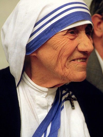 Photograph of St. Teresa of Calcutta smiling, in her white sari with blue stripes.